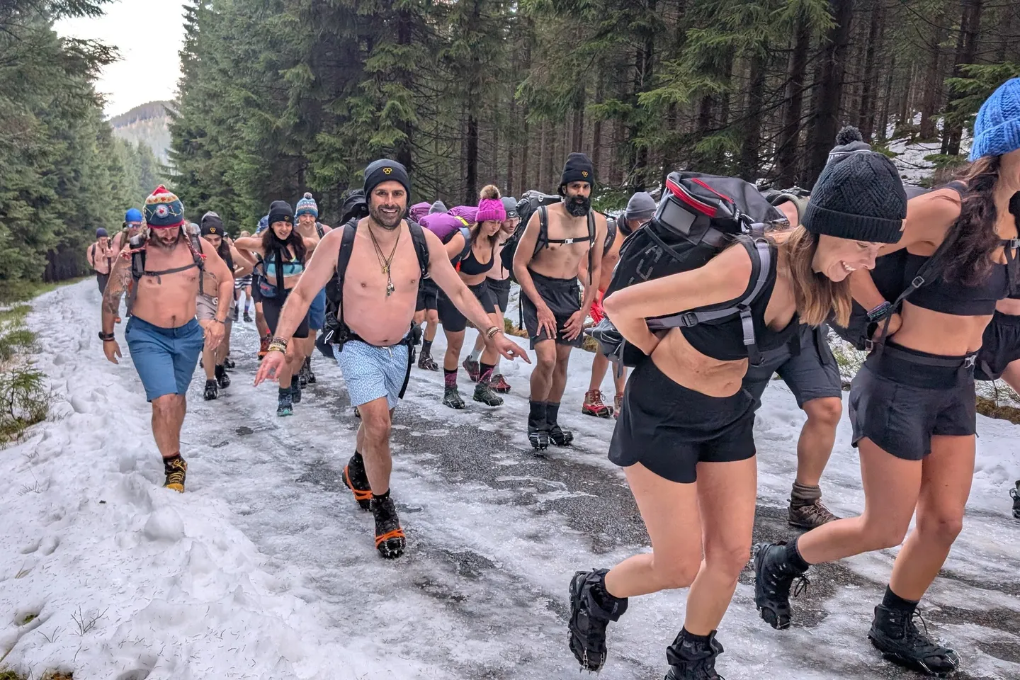 Gruppe wandert leicht bekleidet über einen verschneiten Waldweg – Kältetraining nach der Wim Hof Methode
