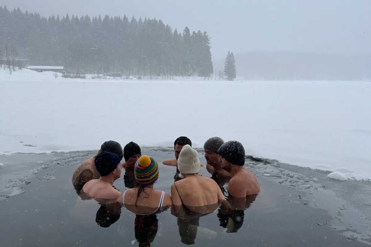 Teambuilding-Gruppe im Eisloch des zugefrorenen Spitzingsees bei Schneefall