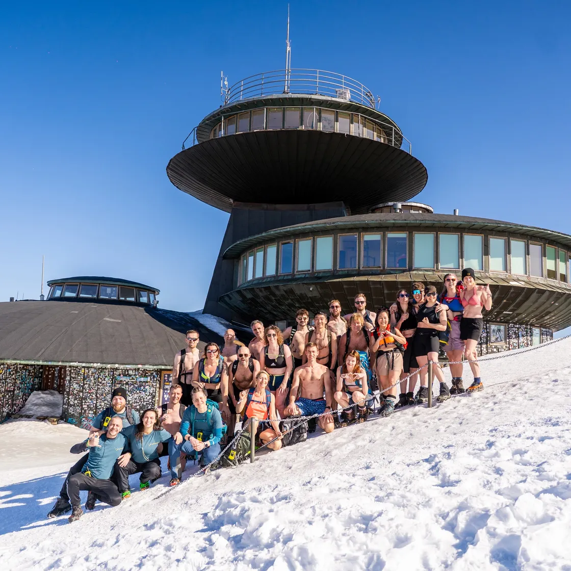 Gruppe in Badekleidung im Schnee vor dem Gipfelgebäude der Schneekoppe